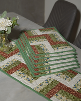 A side-angle view of the table showing the stacked placemats and the runner, emphasizing the repeating zigzag geometry and the professional binding.