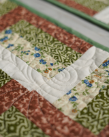 A macro shot of the quilted fabric, highlighting the intricate circular stitching details and the contrast between the floral and lattice prints.