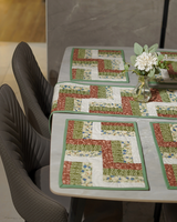 A focused shot of the mats at the head of the table, showcasing the precise craftsmanship of the sage-green borders.