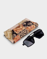 The eyewear case shown at an angle next to a pair of dark sunglasses, demonstrating its practical 7" length and the robust, firm texture of the handcrafted quilting.