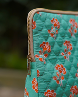 A close-up detail shot of the bag's corner, highlighting the secure cream-toned zipper and polished gold-toned hardware against the quilted textile.