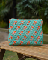 A front-facing view of the laptop bag standing upright on a wooden surface, set against a lush, blurred green garden background.