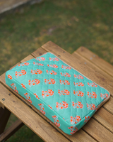 A high-angle perspective of the bag lying flat on a wooden slatted table, emphasizing its structured 2" width and the repeating diamond quilt pattern.
