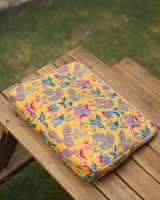 A high-angle perspective of the bag resting flat on a wooden surface, emphasizing the structured 2" width and the continuity of the floral block-print across the entire surface.