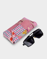 The eyewear case shown at an angle alongside a pair of dark sunglasses, demonstrating its practical 7" length and protective form.