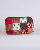 A front-facing studio shot of the Ruby & Cream Chevron Quilted Pouch, showcasing the vibrant patchwork of red zigzags and cream botanical prints.