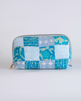A front-facing studio shot of the Ocean Blue Leaf & Tile Quilted Pouch against a clean white background, showcasing the vibrant blue and teal patchwork panels with leaf and geometric motifs.