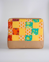 Back view of the quilted laptop bag, highlighting the bright marigold and turquoise geometric and floral patchwork patterns above a solid tan-toned bottom.