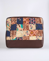 A front-facing view of the cocoa and indigo botanical patchwork laptop bag, highlighting the rich, earthy tones and hand-quilted texture of the textile panels.