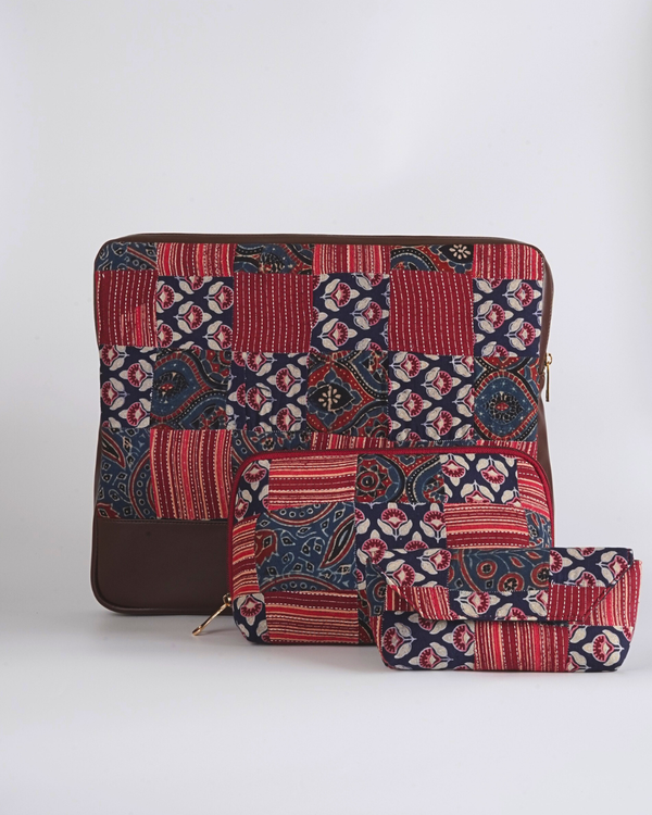 A complete set of the Crimson & Indigo Ajrakh Essentials Trio, featuring the laptop bag, utility pouch, and eyewear case arranged together to show their coordinated patchwork design and tan leather-style bases.
