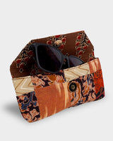 The Vibrant Ikat Eyewear Case shown at an angle next to a pair of sunglasses, demonstrating its practical 7" length and structured, portable design.