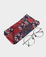 The eyewear case shown at an angle alongside a pair of wire-rimmed glasses, illustrating its practical 7" length and compact, portable design.