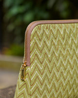 Close-up of the gold-toned metal zipper and the intricate vertical quilting on the sage green fabric.