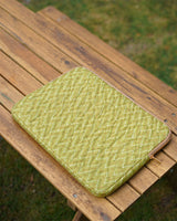 An overhead view of the handcrafted quilted tablet bag resting flat on a wooden outdoor bench.