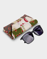 The eyewear case shown at an angled perspective next to a pair of dark sunglasses, illustrating its 7" length and structured, protective shape.
