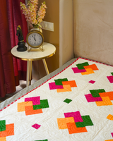 A focused lifestyle shot of the bed and side table, showing how the vibrant colors of the quilt anchor the room's warm aesthetic.