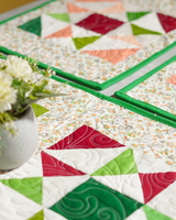 A close-up shot of the vibrant pinwheel patchwork, highlighting the intricate quilting and the contrast between the bold geometric shapes and the micro-floral background.