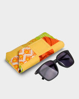The eyewear case shown at an angle next to a pair of dark sunglasses, demonstrating its 7" length and how the structured design provides a secure fit for frames.